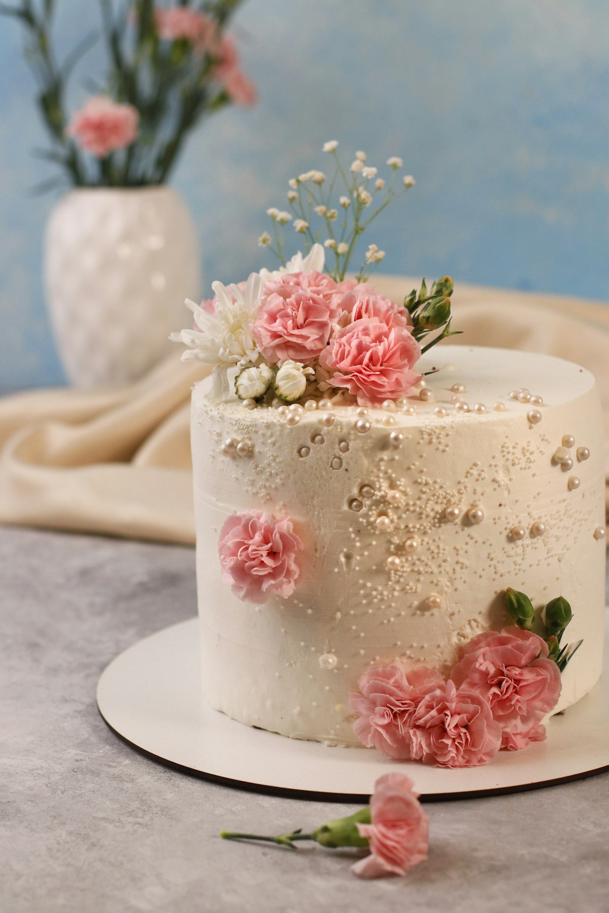 A celebration cake decorated with fresh pink flowers, made by Bella