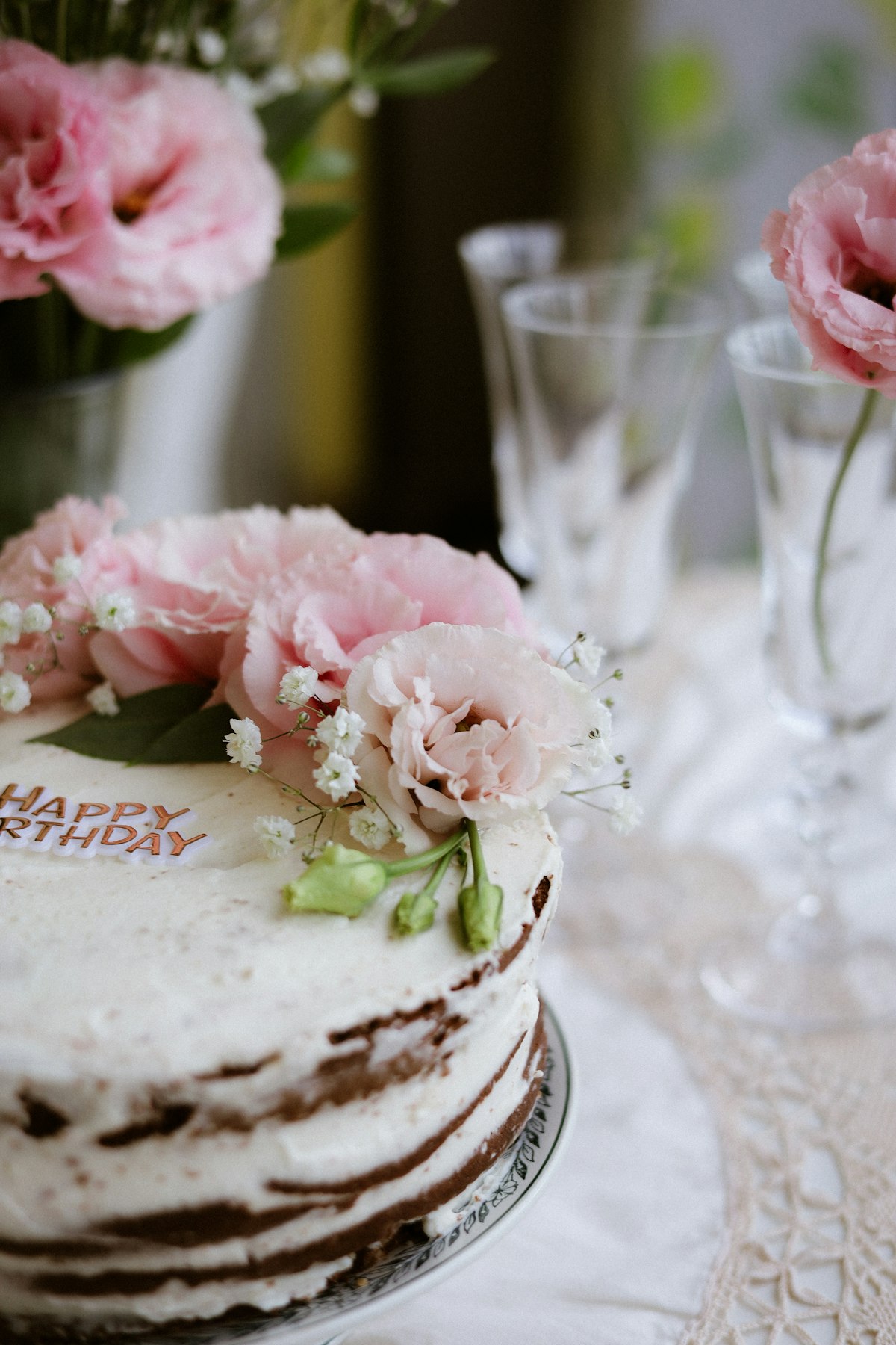 A pink flower-decorated celebration cake in an open gift box